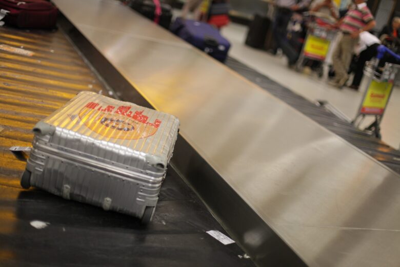 空港の荷物受け取りターンテーブルに流れてくるスーツケース